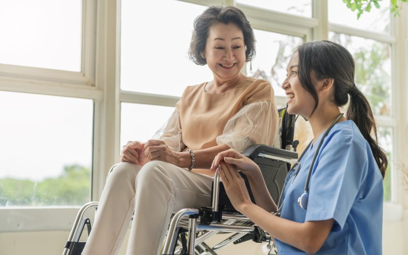 asian-young-caregiver-caring-her-elderly-patient-senior-daycare-handicap-patient-wheelchair-hospital-talking-friendly-nurse-looking-cheerful-nurse-wheeling-senior-patient